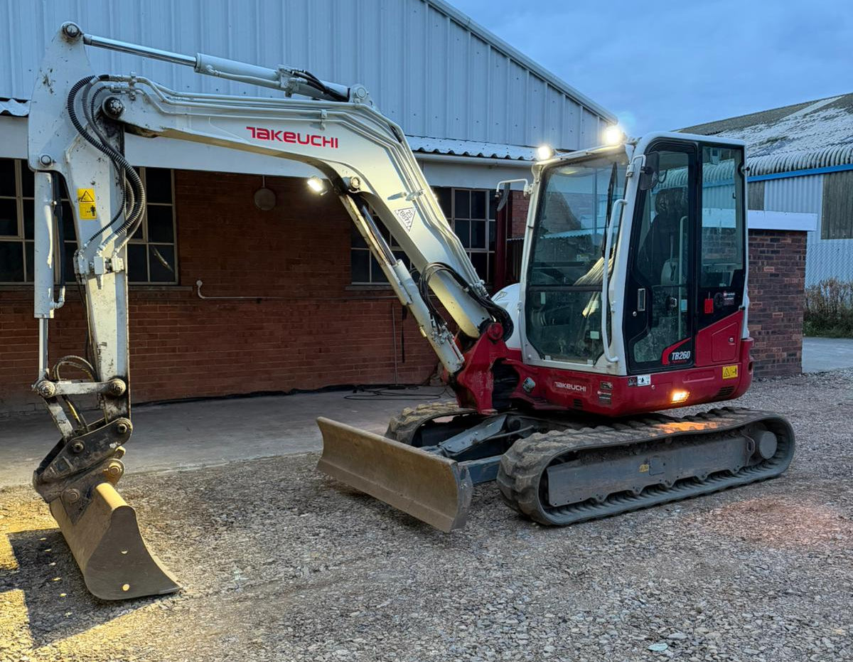 Takeuchi excavator on a gravel surface with a building in the background